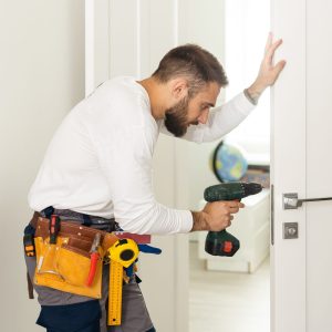 High,Angle,View,Of,Male,Carpenter,With,Screwdriver,Fixing,Door